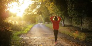 Person walking forward on a sunny path representing the transition out of sober living and into independent recovery at Izzy's House in Ohio