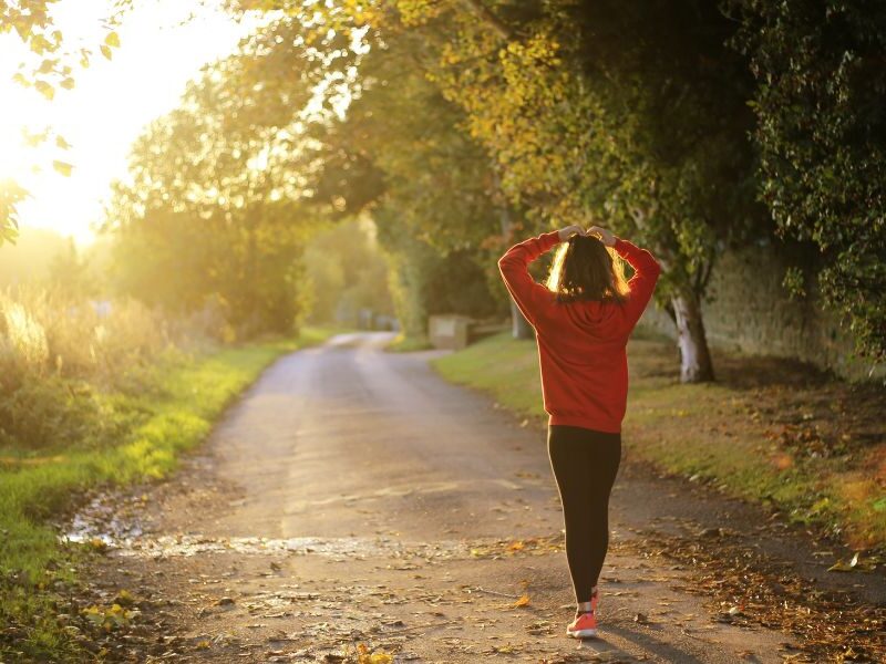 Person walking forward on a sunny path representing the transition out of sober living and into independent recovery at Izzy's House in Ohio