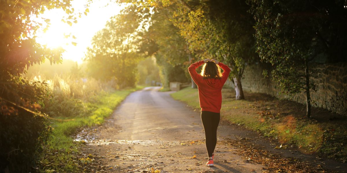 Person walking forward on a sunny path representing the transition out of sober living and into independent recovery at Izzy's House in Ohio